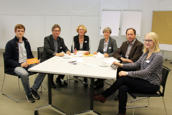Sechs Personen sitzen an einem Tisch im Konferenzbereich der FH Bielefeld.