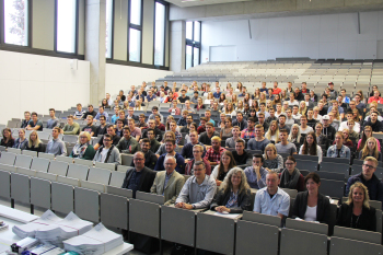 Rund 230 Studierende, Dozentinnen und Dozenten sowie Tutorinnen und Tutoren sitzen auf den Stühlen im Audimax.