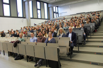 Teilnehmer und Dozenten sitzen in den Stuhlreihen des Audimax.