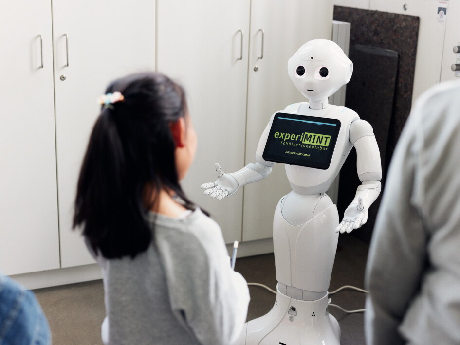 Ein Mädchen steht vor einem pepper-Roboter