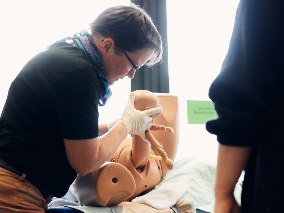 Eine Frau zeigt den Geburtsvorgang an einer Schwangerschafts-Simulation