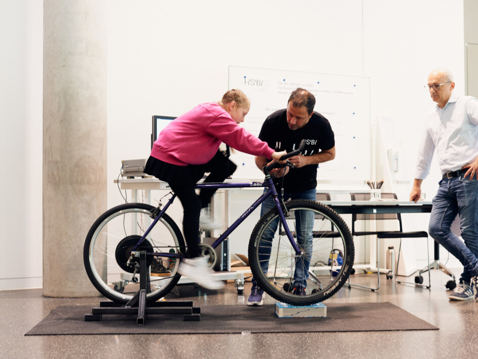 Ein Mädchen sitzt auf einem stationären Fahrrad, das Energie erzeugt