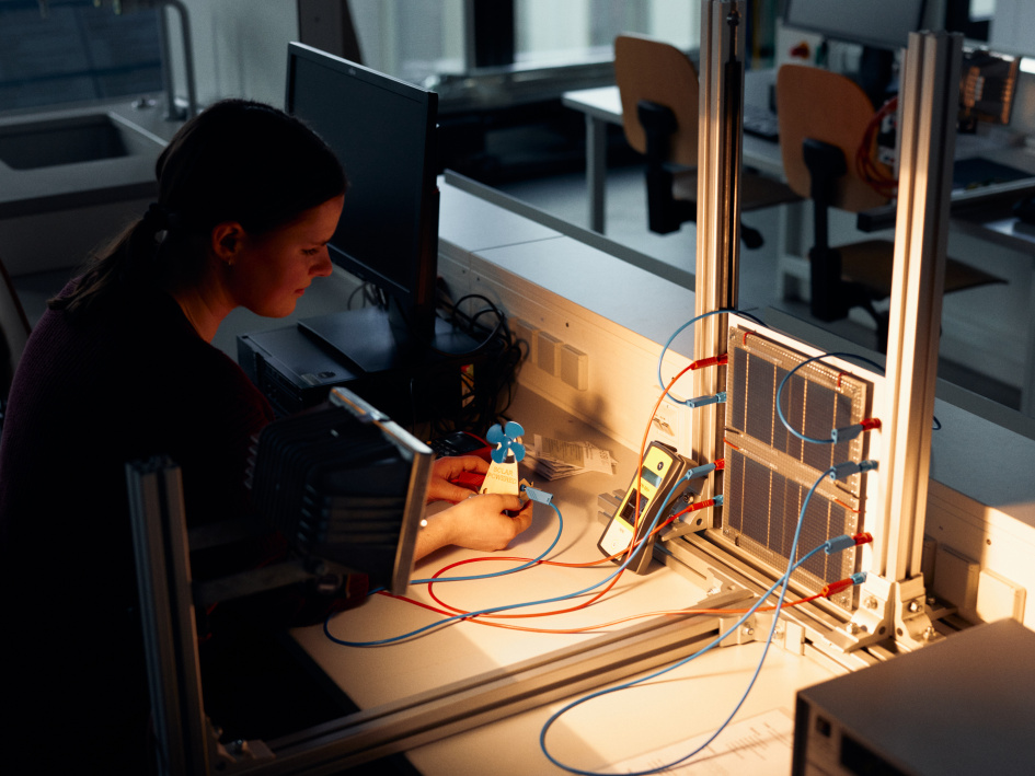 Eine Frau sitzt vor einer beleuchteten kleinen Solarzelle