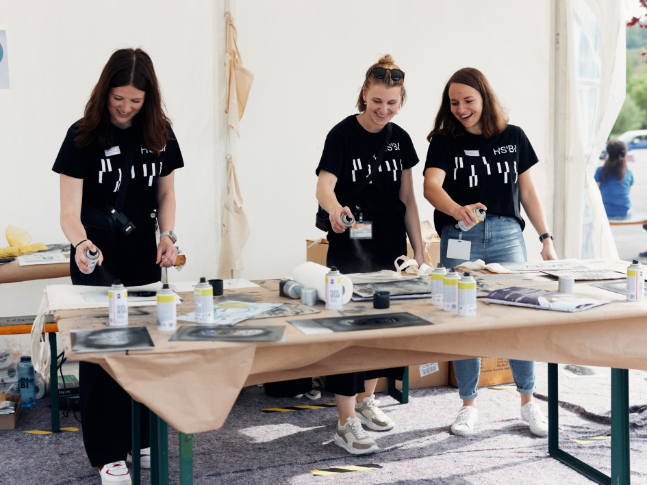 Drei Frauen besprühen Jutebeutel