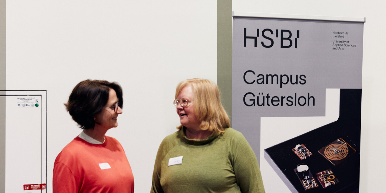 Zwei Frauen stehen vor einem Aufsteller Campus Güterslo