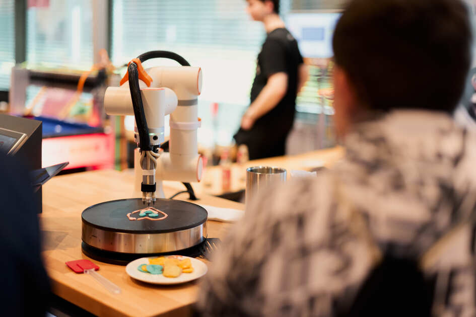 Foto: Ein Roboterarm spritz Pancake Teig auf eine Platte