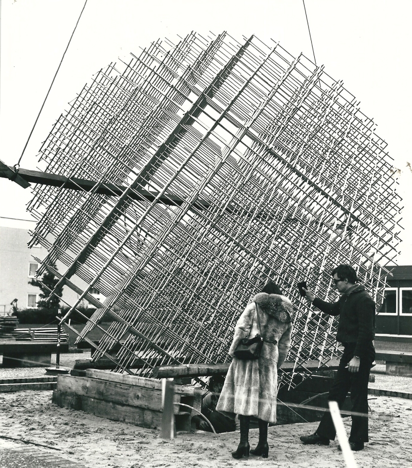 zwei Personen stehen vor dem kugelförmigen Kunstwerk