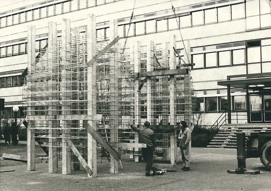 Das Kunstwerk steht von Balken gestützt vor dem ehemaligen Gebäude des Fachbereichs Sozialwesen