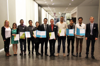 11 Personen , geschlechtergemischt, stehen in der Magistrale mit Urkunden.