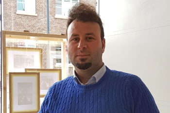 EIn Mann steht vor einem Fenster und lächelt in die Kamera