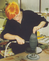 Professorin Friedlinde Burkhardt arbeitet Linien in eine Tonvase ein.