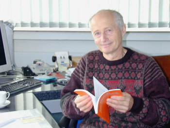 Professor Dr. Helmut Günther sitzt am Schreibtisch und blättert in einem Buch.
