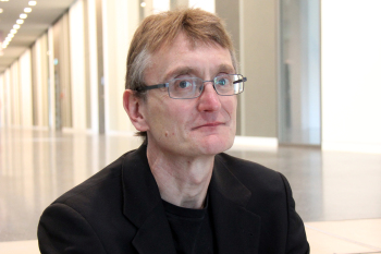 Portraitbild von Prof. Dr. Alexander Haubrock sitzend mit Blick in die Magistrale.