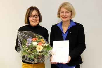 Porträtaufnahme zweier Frauen, eine mit Blumenstrauß, die andere mit Urkunde