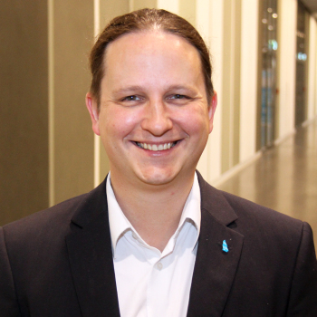 Portraitfoto von einem Mann mit weißem Hemd und schwarzem Sakko.