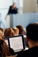 Studierende im Hörsaal. Man sieht den Bildschirm eines Studenten.