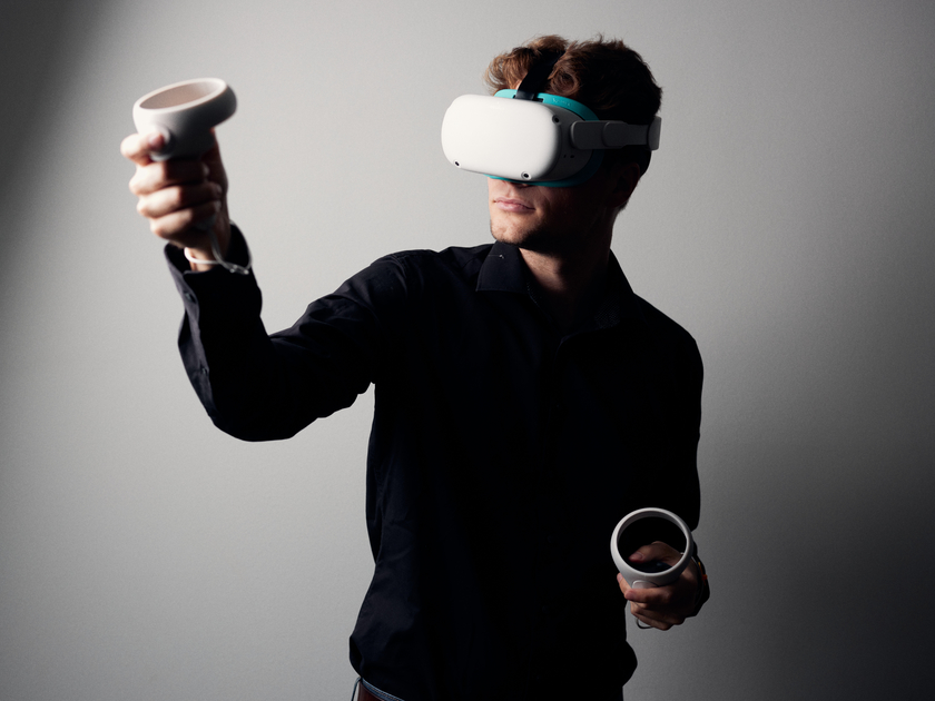 Eine Person trägt eine VR-Brille auf dem Kopf und hat zwei Controller in der Hand.