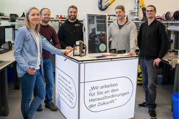 Vier Personen stehen neben einem Messestand