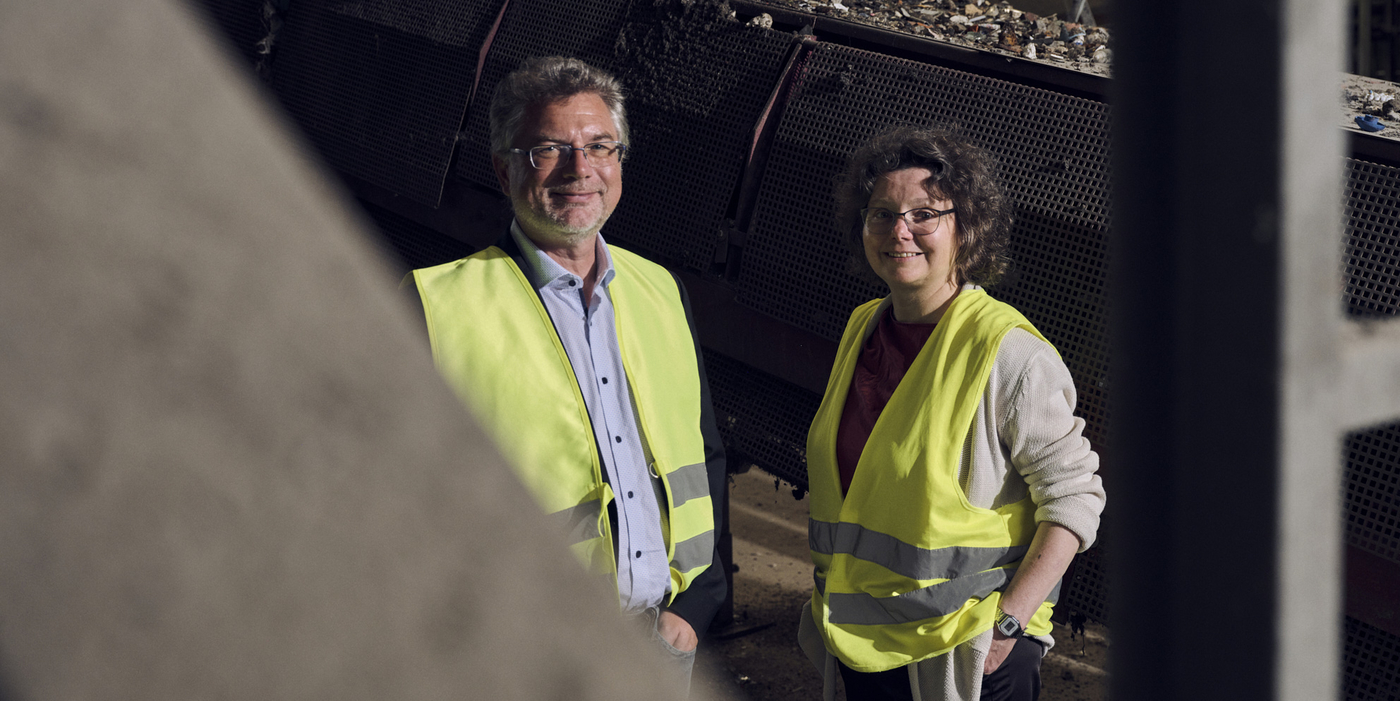 Von links stehen Professor Christian Schröder und Heike Wulf von der HSBI in vor einem Förderband mit Abfall