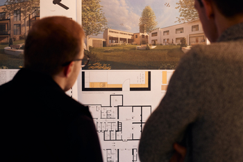 Zwei Personen betrachten architektonische Zeichnungen auf einer Veranstaltung