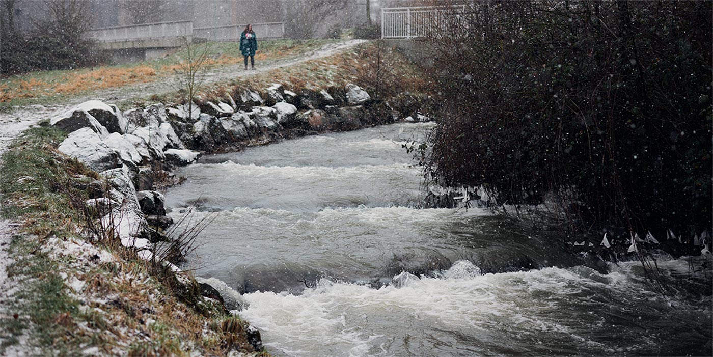 Eine Frau steht an einem überschwemmten Fluss