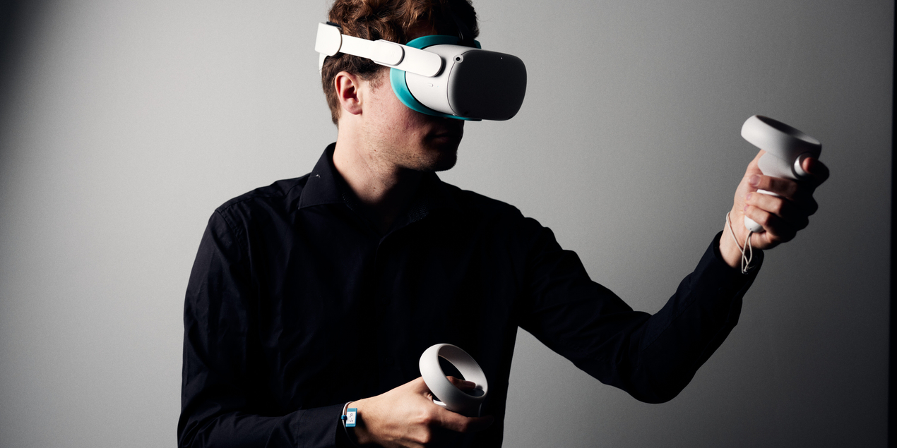 Ein Teilnehmer des VirDiPa Projekts hat eine VR Brille auf die den Großteil seines Gesichts bedeckt In seinen Händen hält er ringförmige Controller mit denen die im Projekt entwickelte digitale Übung absolviert werden kann