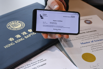 Moritz Mey hält ein Handy in die Kamera, im Hintergrund eine chinesische Urkunde