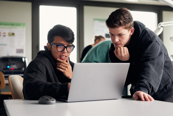 Zwei Studierende arbeiten an einem Laptop